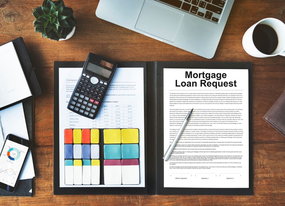 Mortgage loan request form with calculator and laptop on desk.