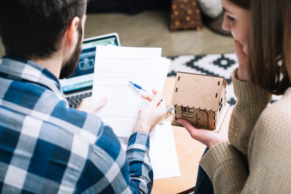 Two people discussing a small architectural model and documents.