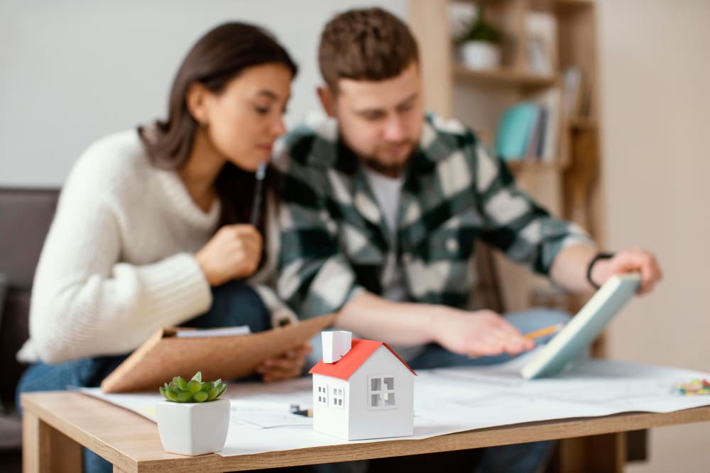 Couple reviewing finances with a small house model in front.