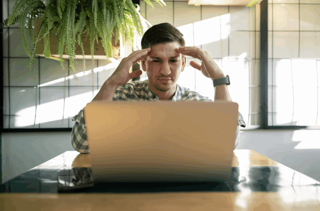 A man sitting at home considering his loan options on a laptop.
