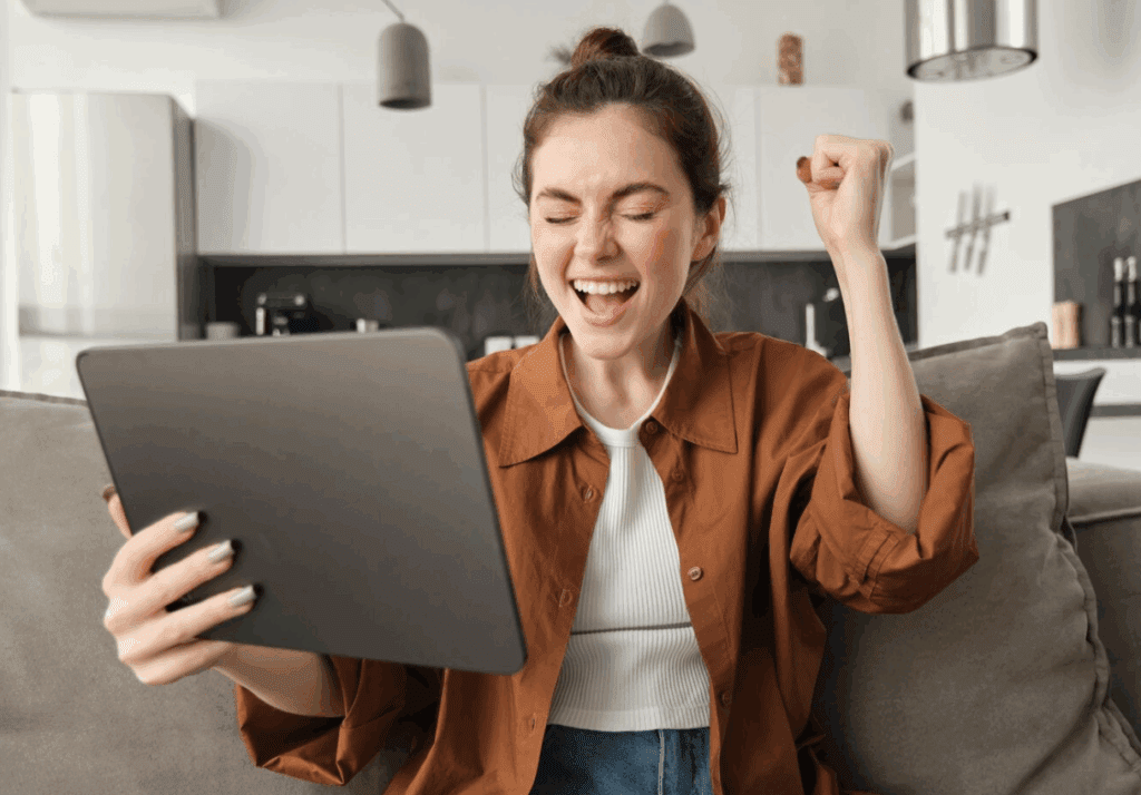 Woman celebrating success while looking at tablet.